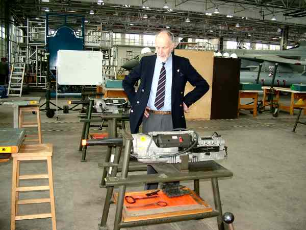 Man standing in an aircraft hanger looking at a piece of equipment.