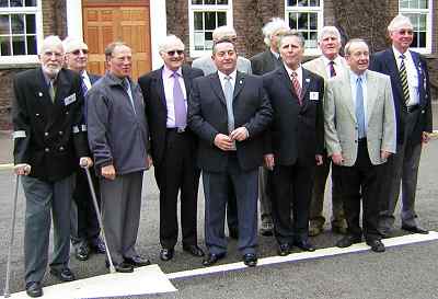 A small group of men in fleece jackets posing for a photograph outside a building