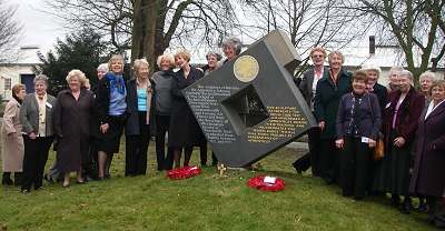 74th Entry ladies at the Tribute. A group of women stood in a long line with a box-like structure in the centre.