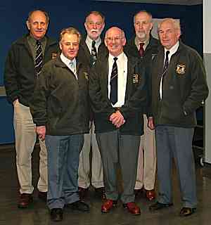 A small group of men in fleece jackets posing for a photograph outside a building